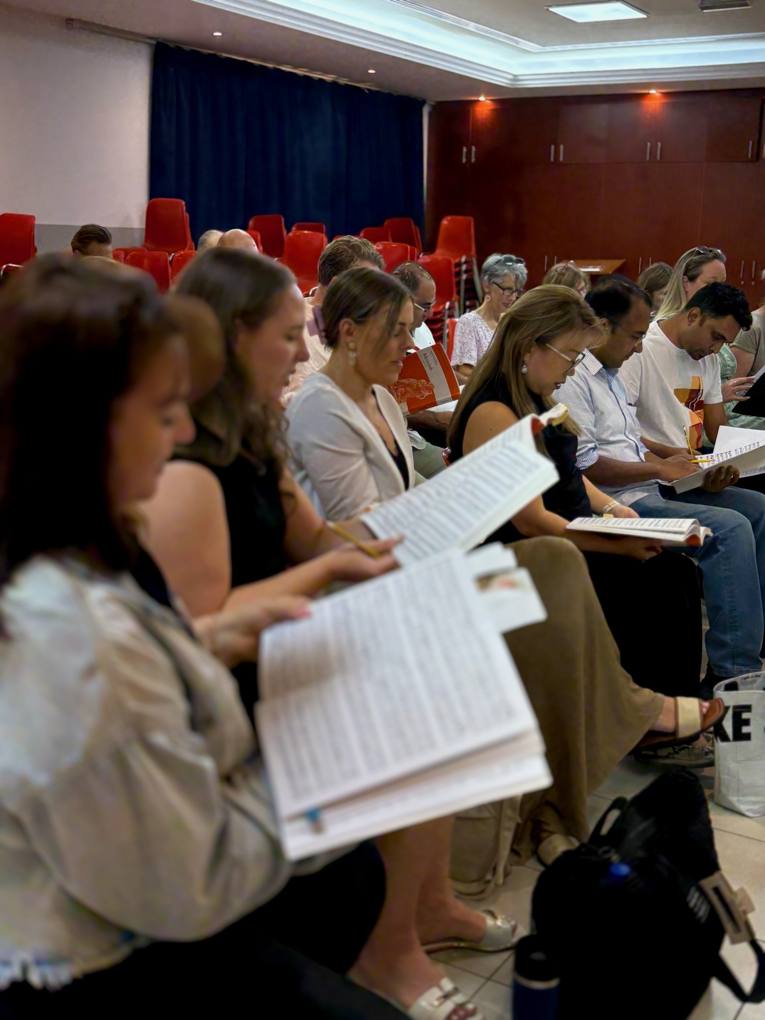 Dubai Singers members reading music together at rehearsal